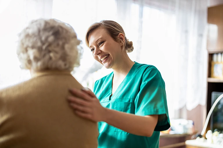 Our Mission: Friendly nurse supporting an elderly lady